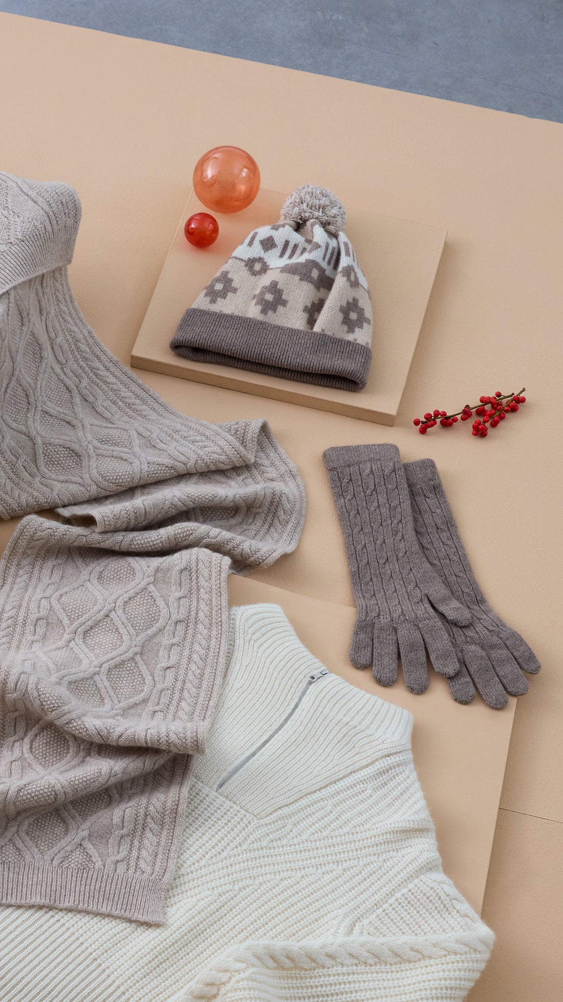 cashmere hat, cashmere scarf, cashmere gloves, cashmere sweater on beige paper ensembled together with Christmas gifts