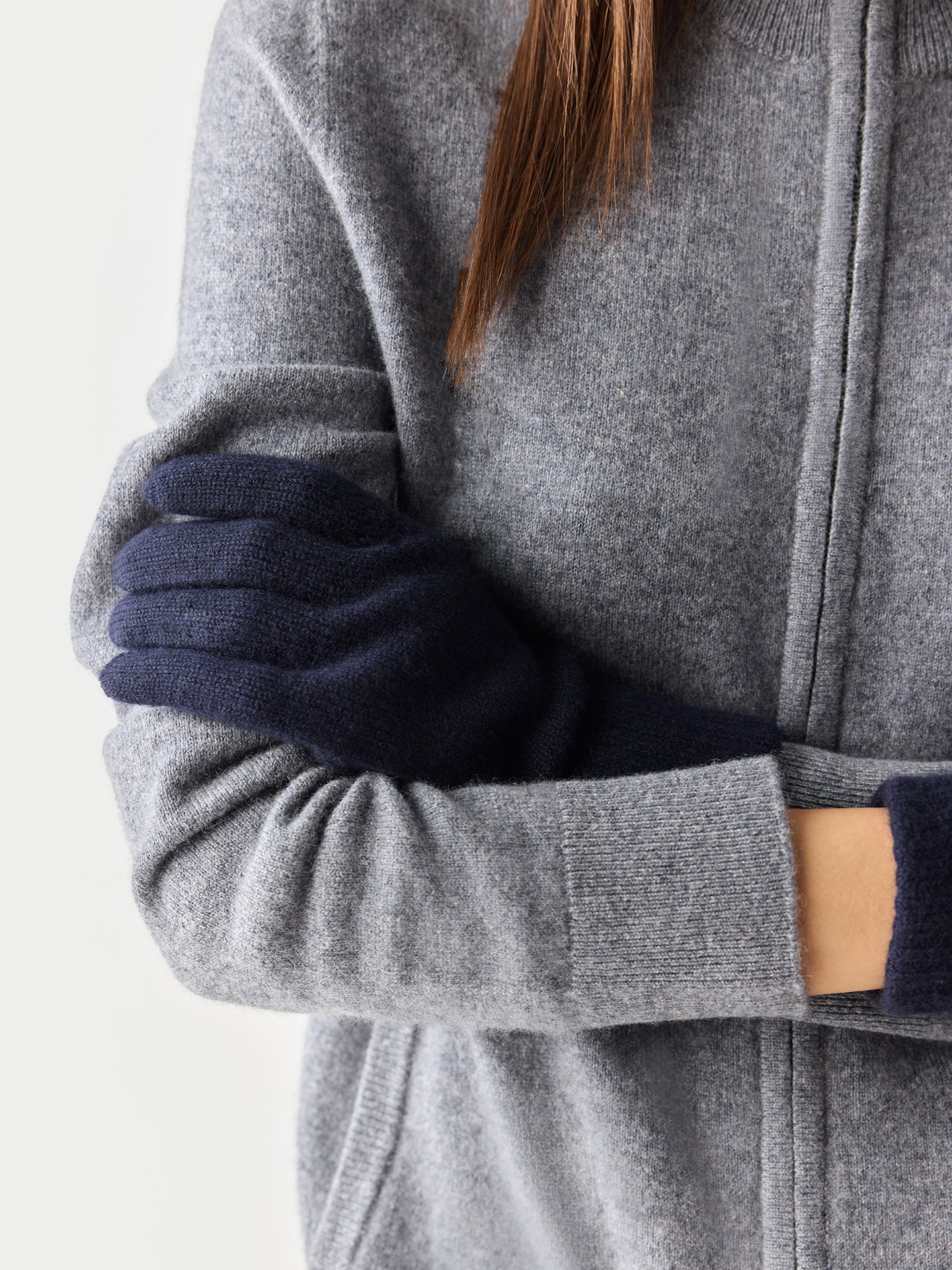 Person wearing a gray coat with navy gloves on a light background